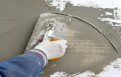 Worker spreading stucco on side of commercial building.